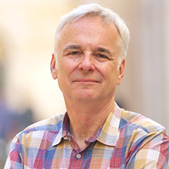 Kenneth Foster smiling in a plaid shirt outside.