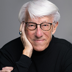 Photo of a man with glasses and white hair wearing a black turtleneck sweater.