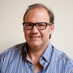 Image of a man in glasses wearing a blue striped shirt.