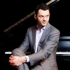 formal portrait of Steven Vanhauwaert in formal attire seated at a piano