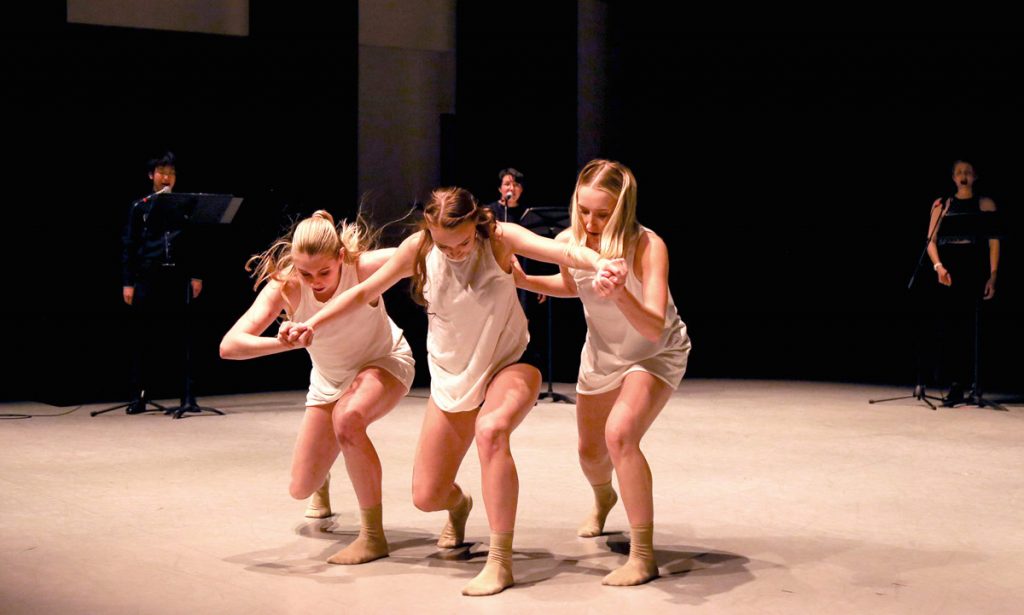 Lillie Pincus, Whitney Hester, and Kaylin Sturtevant dance in the foreground as musicians Hao Chen Wang, Clara Valenzuela, and Mary Pettygrove perform in the background.
