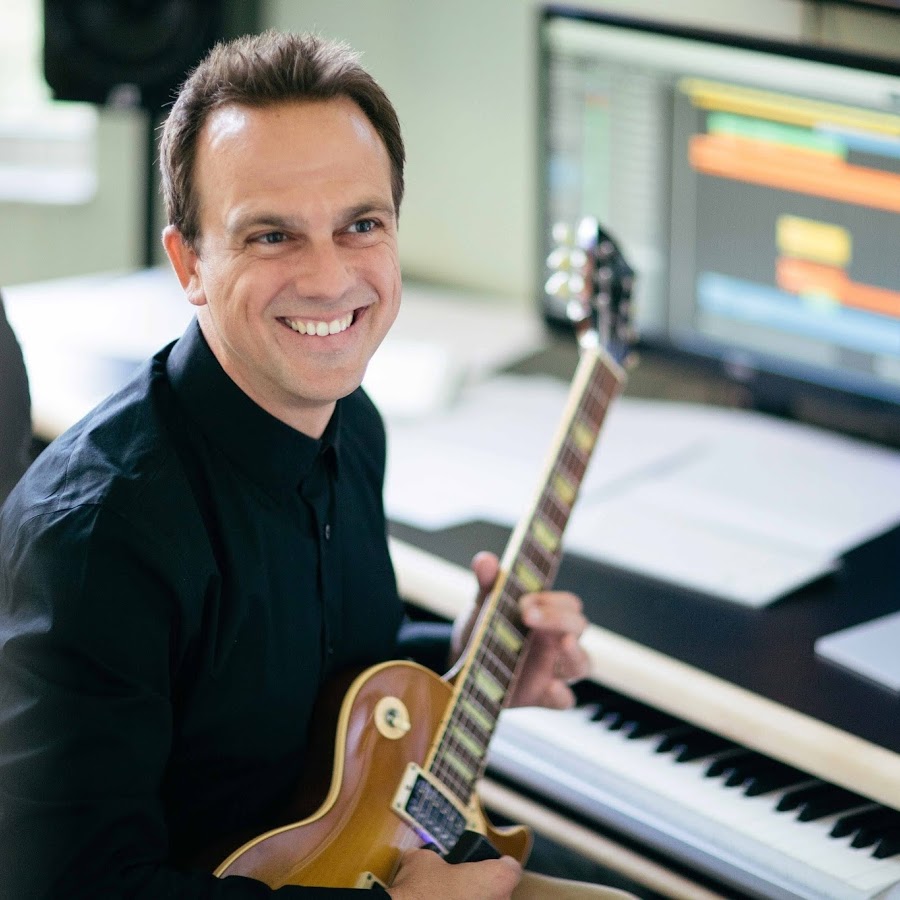 Carlos Rafael Rivera holding guitar in a recording space