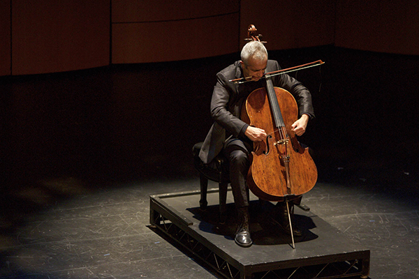 Photo of cellist on stage under spotlight 