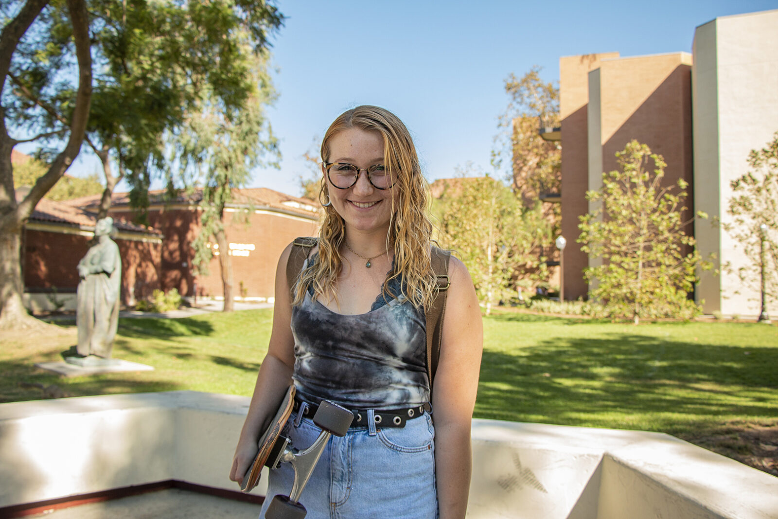 Portrait of Molly Sibley holding skateboard on campus 