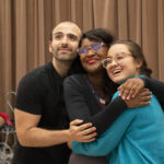 Three cast members embrace while rehearsing opera