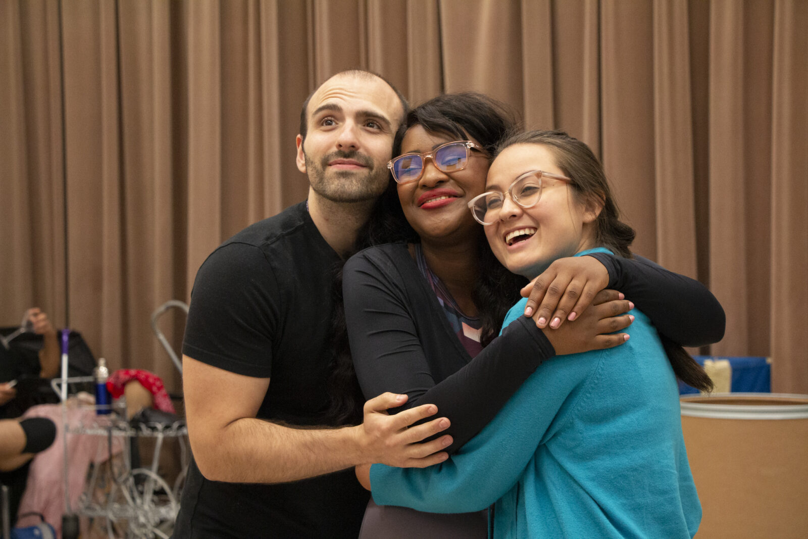 Three cast members embrace while rehearsing opera 