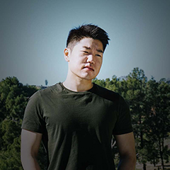 Peter Shin photographed outdoors with greenery behind him