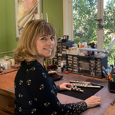 Cynthia Kelley at flute repair desk with instrument and tools