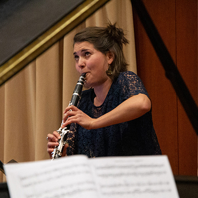 Woman playing clarinet, viewed through open lid of a piano