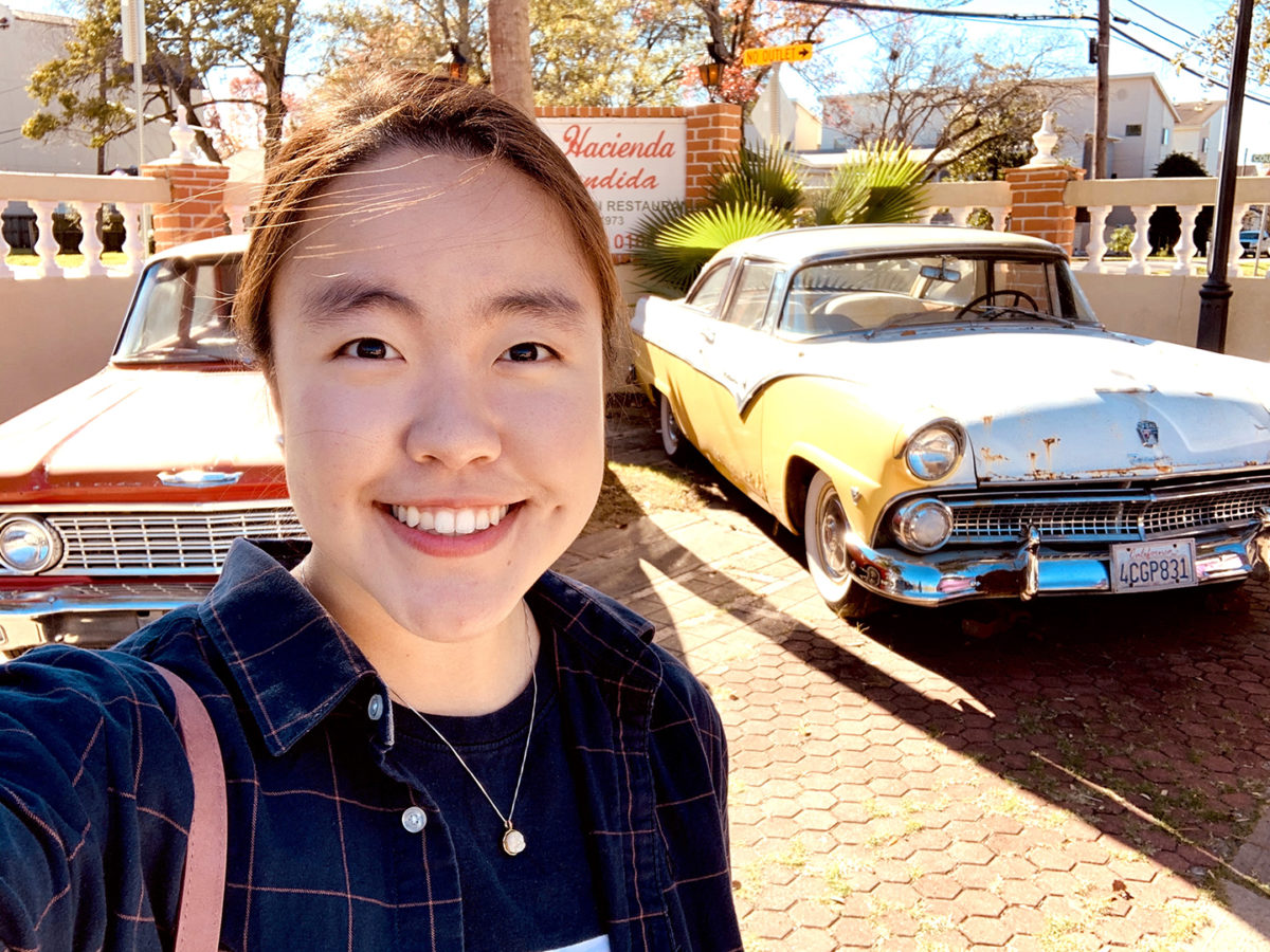 Linda Diaz standing beside classic cars 