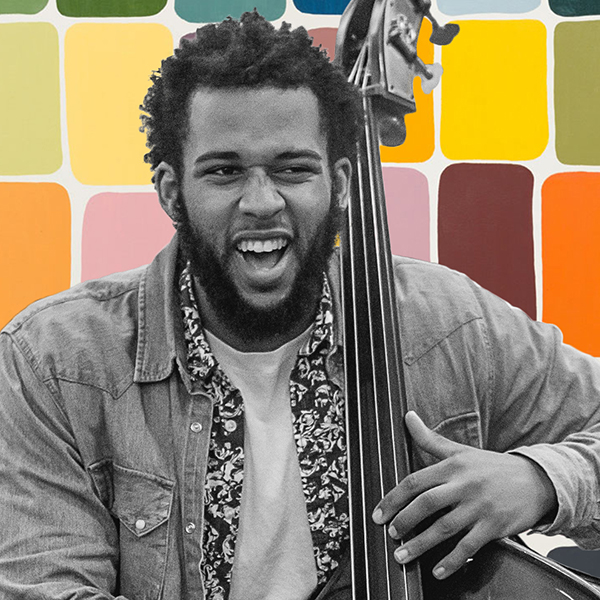 A black and white image of a double bassist playing with a colorful background