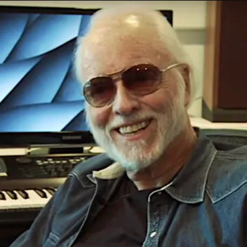 Perry Botkin Jr. wearing sunglasses and sitting beside a piano keyboard