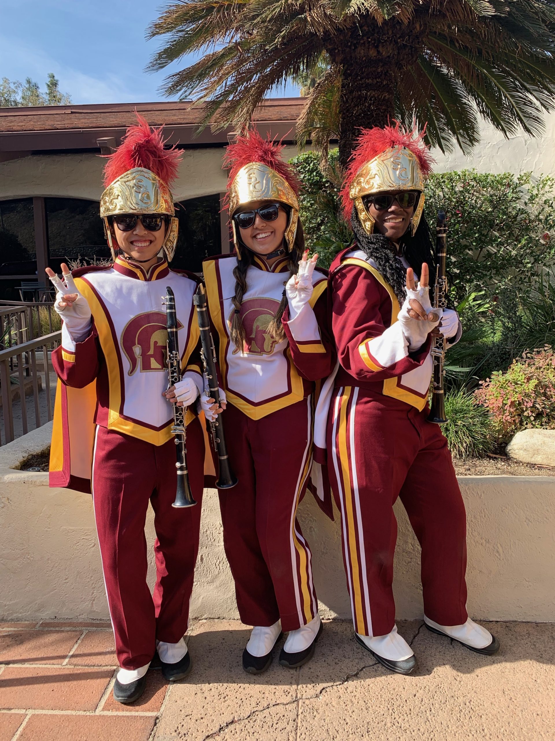 Three students in maroon & gold marching band attire, holding reed instruments