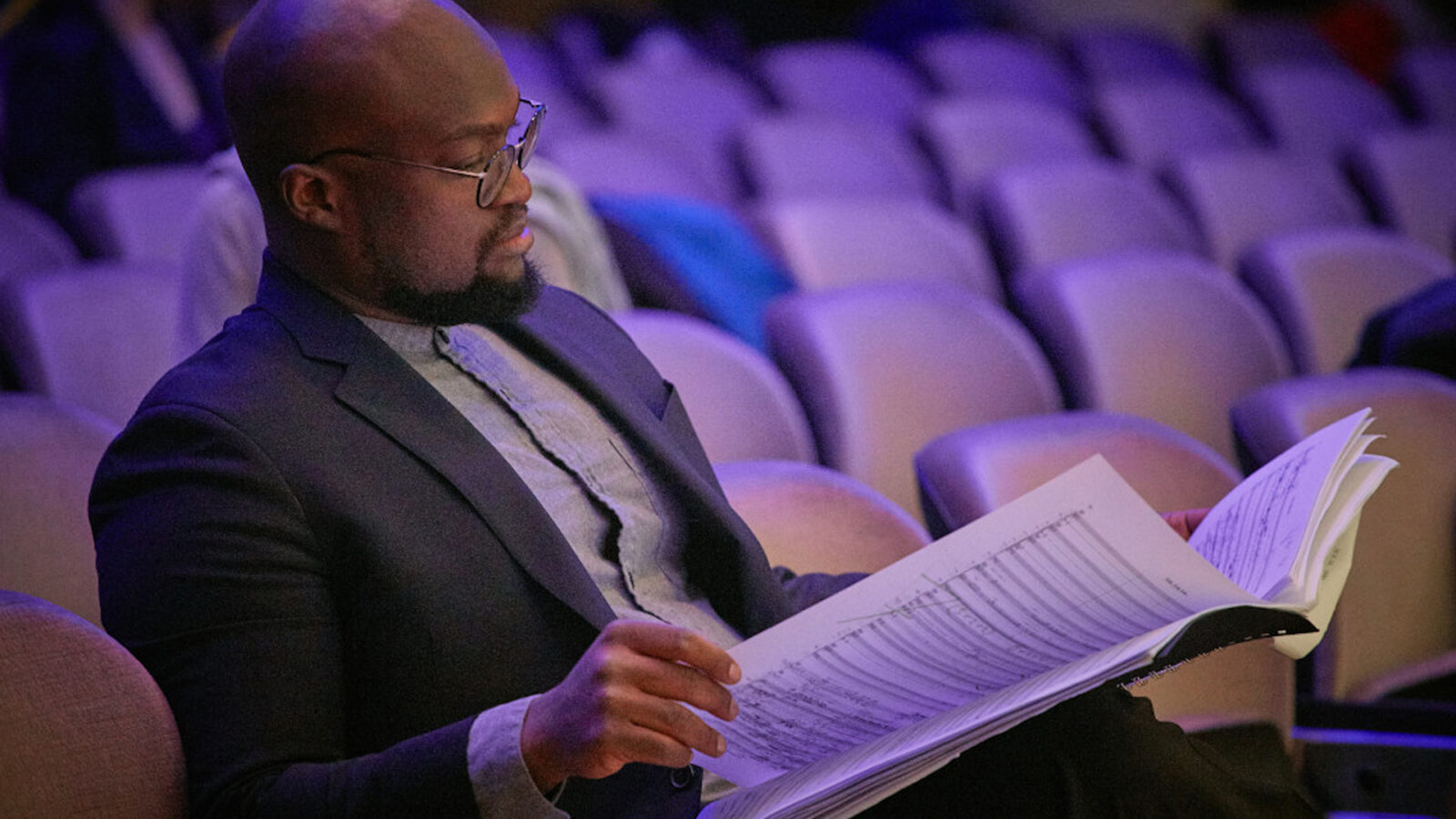 Vimbayi Kaziboni reads sheet music in an auditorium 