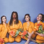 Photo of jazz group saje, wearing yellow uniforms holding flowers.