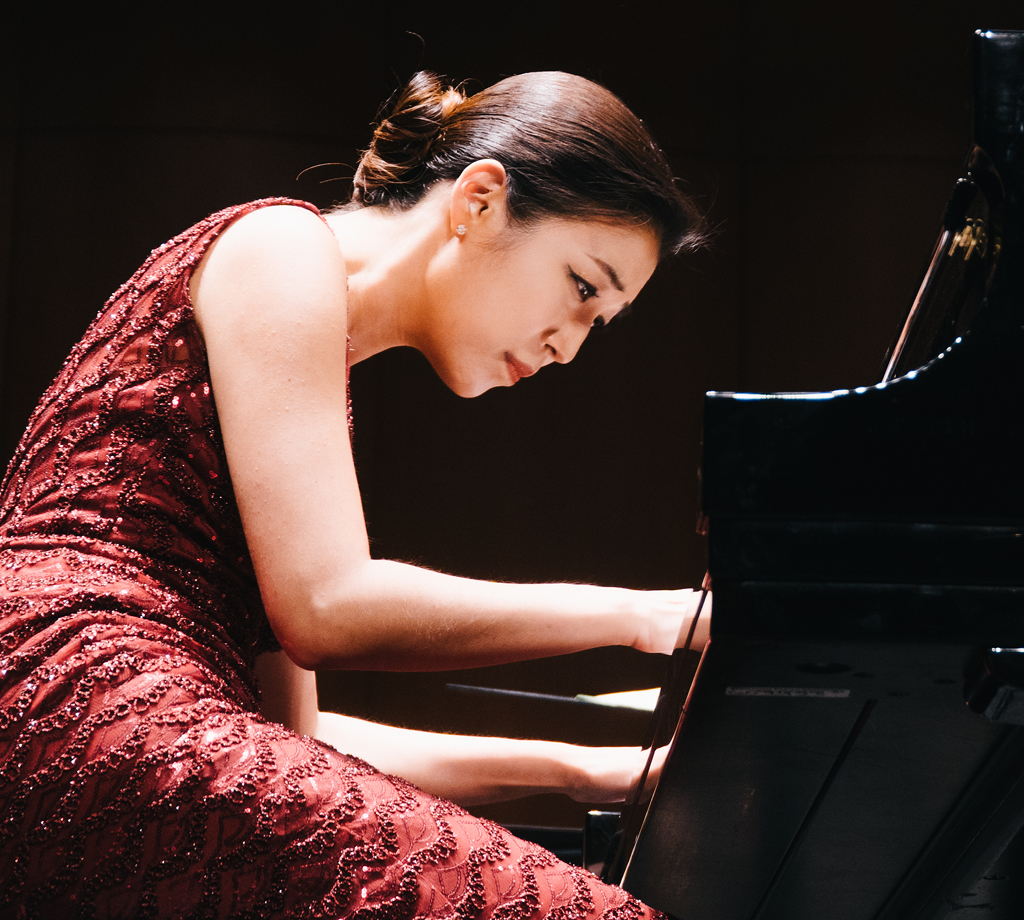 Pianist on stage in concert attire, playing at Bovard Auditorium.