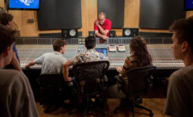 Students gather around a studio mixing board