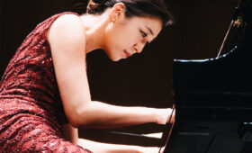 Image of woman seated, playing piano.