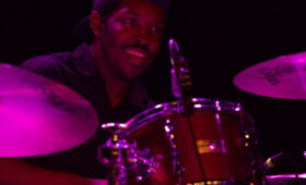 Popular Music drummer performing onstage with purple light