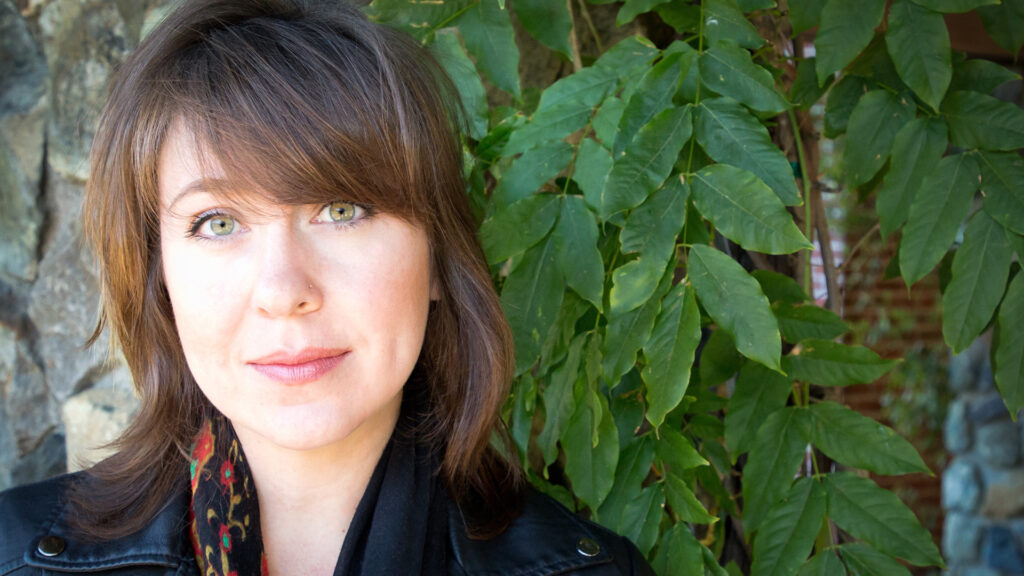 Photo of Danielle Dupre outdoor in front of leafy tree.