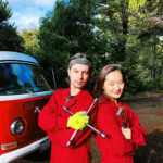 Photo of two violinists posing outside their VW bus