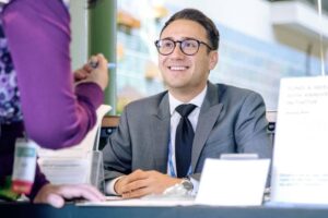 Jonathan Rios greets people at a reception table outdoors. 