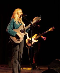 Two students perform the acoustic and electric guitar onstage. 