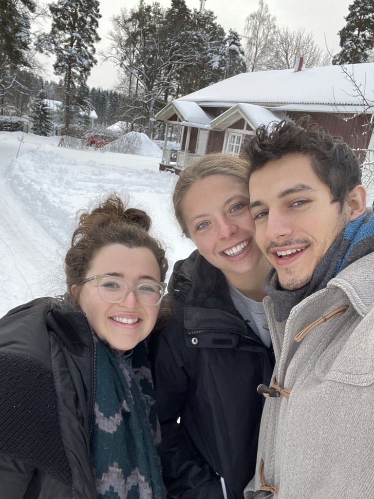Three students pose for a picture in a beautiful snowy landscape. 