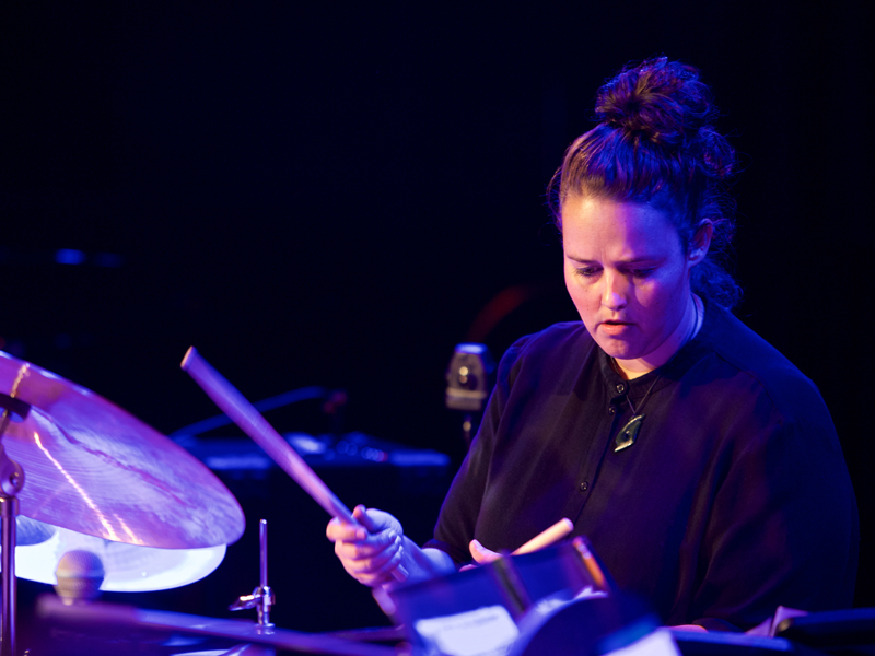 A USC Thornton student in dark attire plays the drums onstage. 