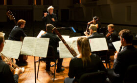 Conductor leads a chamber orchestra in rehearsal.