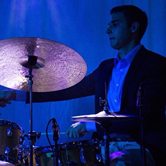Photo of jazz drummer playing drum kit and cymbals kit in blue light