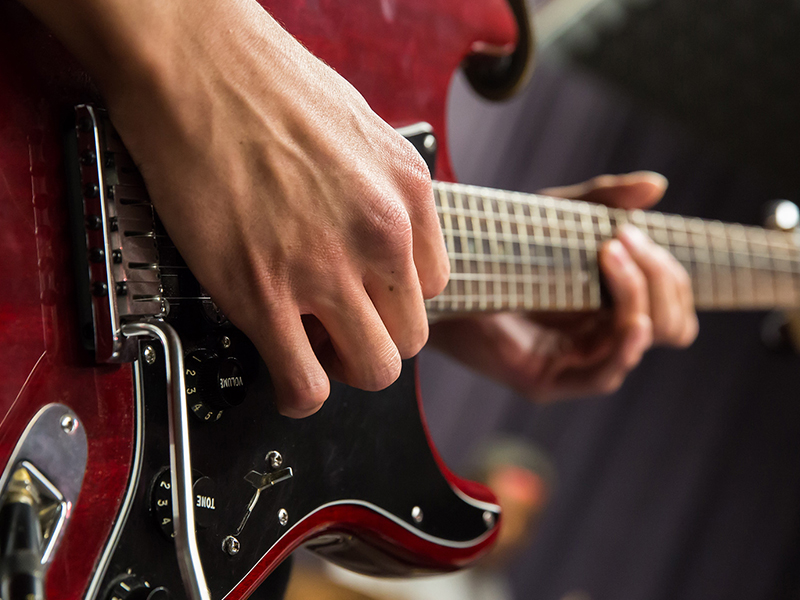 This picture shows the hands of a member playing the electric guitar.