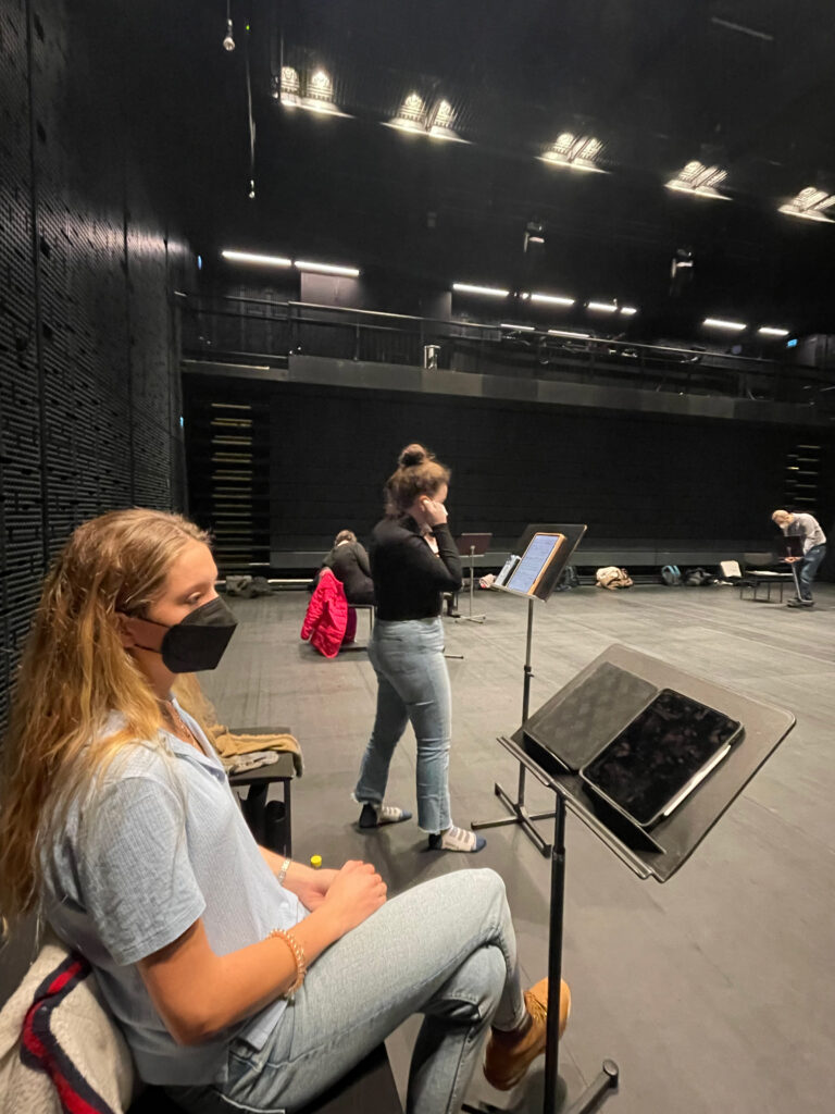 Two students are seen here with music stands in this first of three pictures showing a rehearsal taking place.