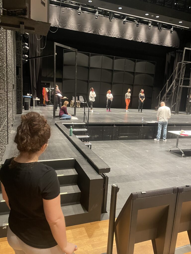 First of three pictures showing a rehearsal taking place onstage indoors