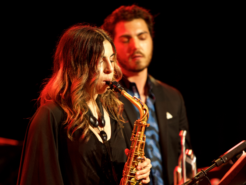 Two USC Thornton students in black concert attire play the saxophone and trumpet onstage. 