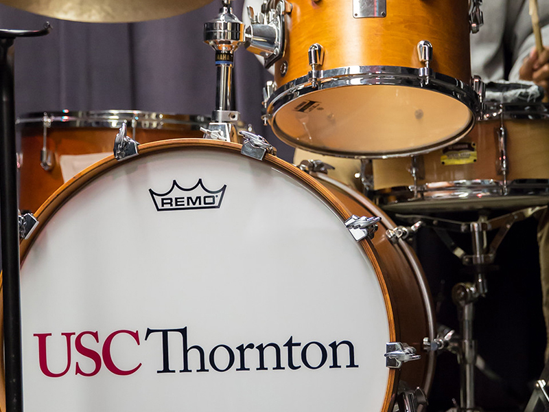 This picture shows a drumset with the logos Remo and USC Thornton. 