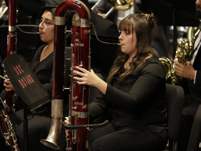 A USC Thornton students in concert attire plays the contrabassoon with the rest of the Thornton Winds in a concert program. 