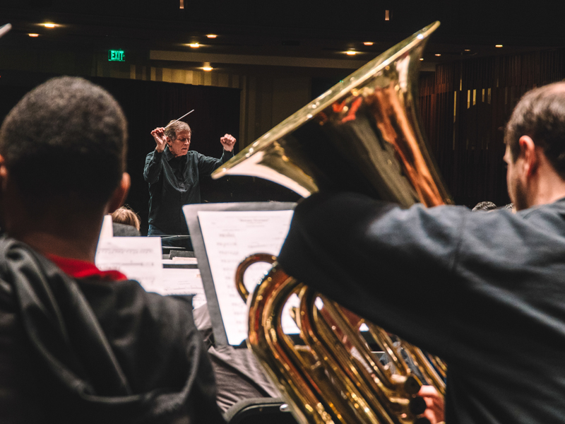 This is a close-up view of a French horn player performing with Composition faculty member Frank Ticheli on the podium for Winds & Percussion.