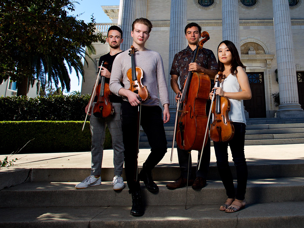 Photo of a string quartet standing on the steps of a historical building.