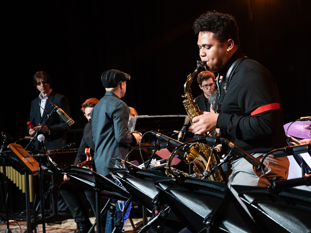 Jazz saxophonist plays a solo on stage with a jazz orchestra.