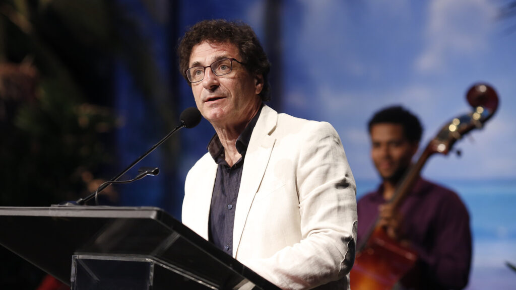 Robert Cutietta in a white jacket speaking at a lectern.