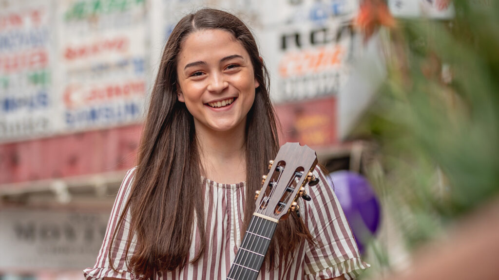 Photo of a smiling classical guitar student outside a shopping center in downtown Los Angeles.