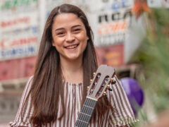 Photo of a smiling classical guitar student outside a shopping center in downtown Los Angeles.
