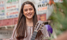 Photo of a smiling classical guitar student outside a shopping center in downtown Los Angeles.