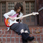 Photo of Eliza Petrosyan playing an electric guitar outside.