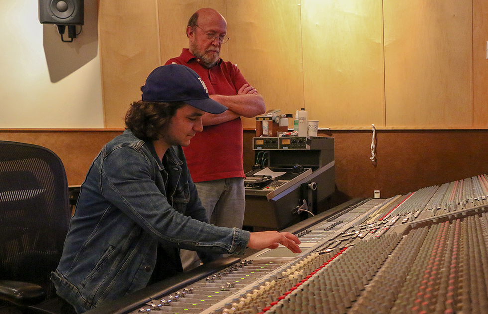 Photo of Joey Messina Doerning at a mixing console with faculty member Dick McIlvery.