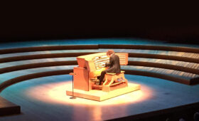 An organist playing pipe organ on stage at Walt Disney Concert Hall.