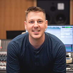Photo of Christian Amonson in front of a mixing console in a sound studio