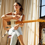 Photo of Molly Miller holding a guitar in the sunlight