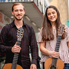 Photo of two students holding classical guitars outside in downtown Los Angeles.